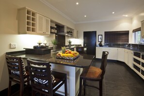 A modern kitchen with a central island, built-in cabinets, and a dining area with chairs.