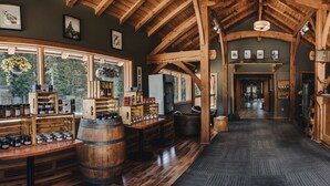 A rustic interior with wooden beams, a bar area, and a view through large windows. - Heather Mountain Lodge (Golden)