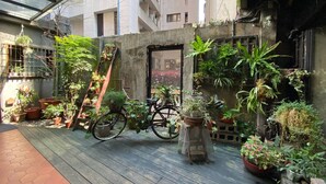 A rooftop garden with potted plants, a bicycle, and a metal birdcage. - Cho Hotel (Taipei)