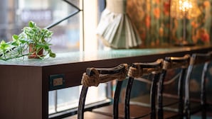 A bar area with a wooden counter, a potted plant, and a decorative lamp. - Cho Hotel (Taipei)