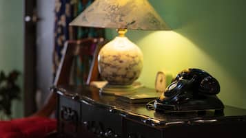 A desk with a lamp, a rotary phone, and a bowl.