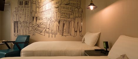 Een hotelkamer met twee bedden, een bureau en een stoel. Op de muur bevindt zich een muurschildering met diverse figuren en tekst.