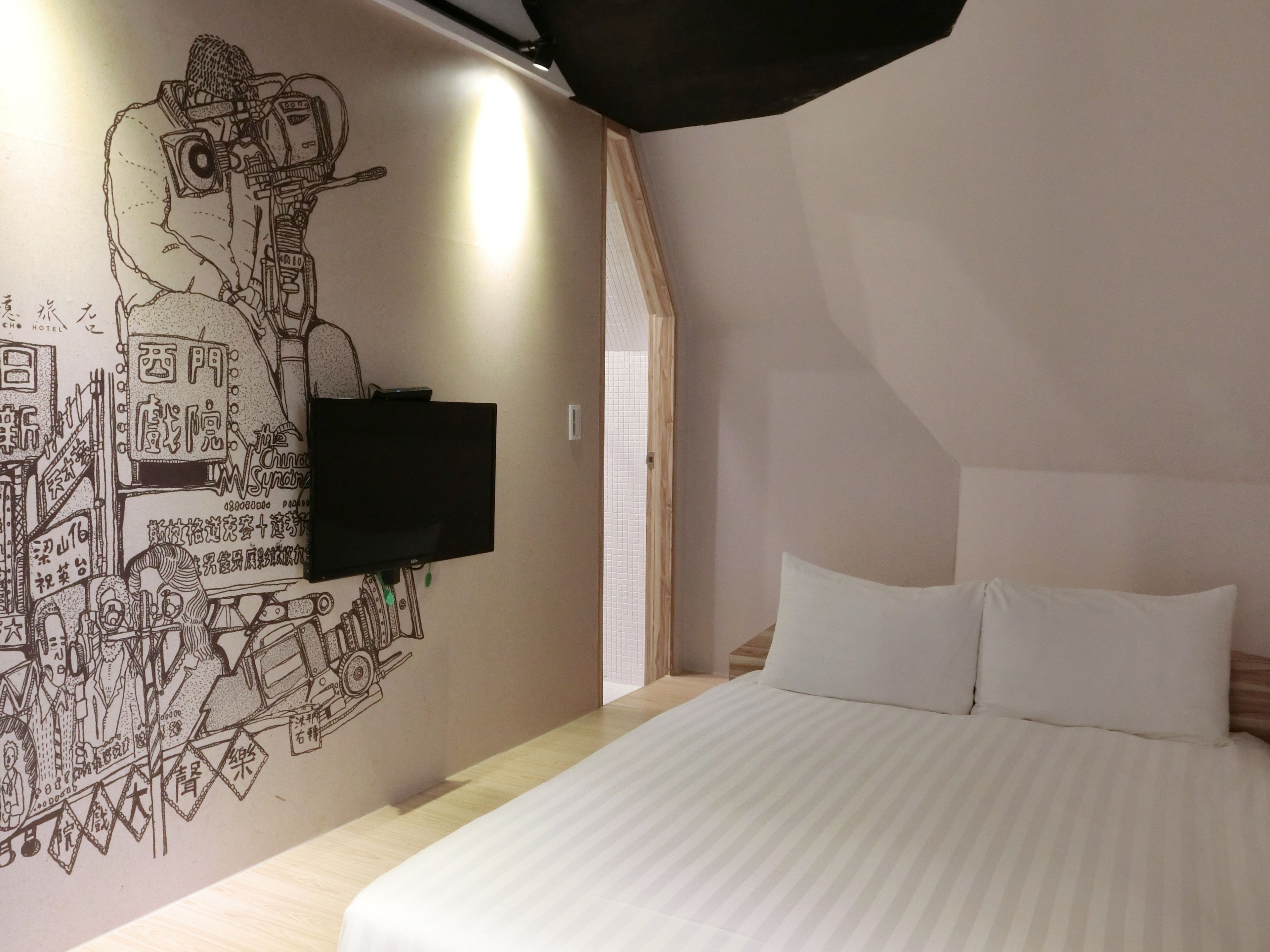 A bedroom with a bed, a flat-screen TV mounted on the wall, and a wall with a detailed mural.