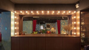A room with a vanity mirror, wooden cabinet, and a mirror above the mirror with lights. - Cho Hotel (Taipei)