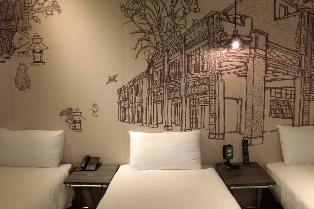 Une chambre d’hôtel avec deux lits, une fresque murale, un téléphone et une télécommande sur la table de chevet.