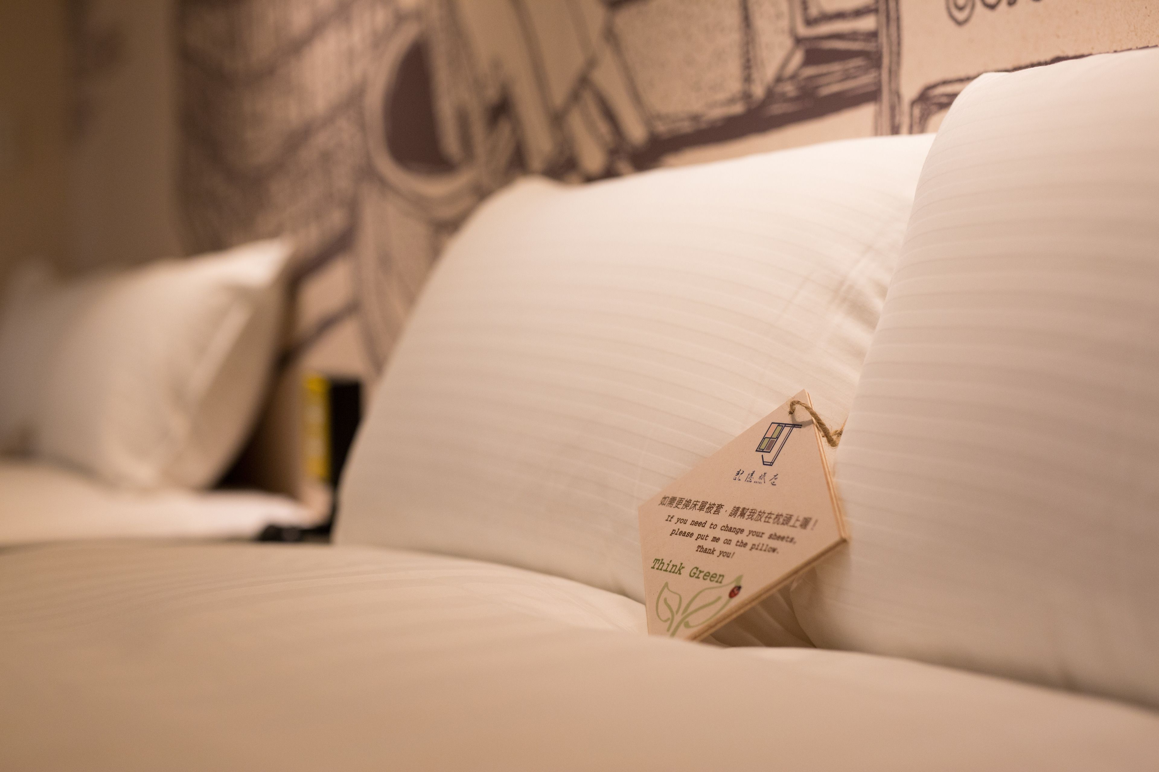 A bed with a pillow that has a tag with text on it.