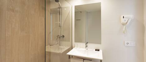 A modern bathroom with a glass-enclosed shower, a white sink, and a hairdryer mounted on the wall.