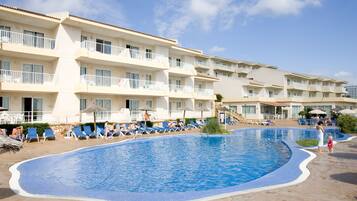 A hotel with a large swimming pool, multiple balconies, and sun loungers.