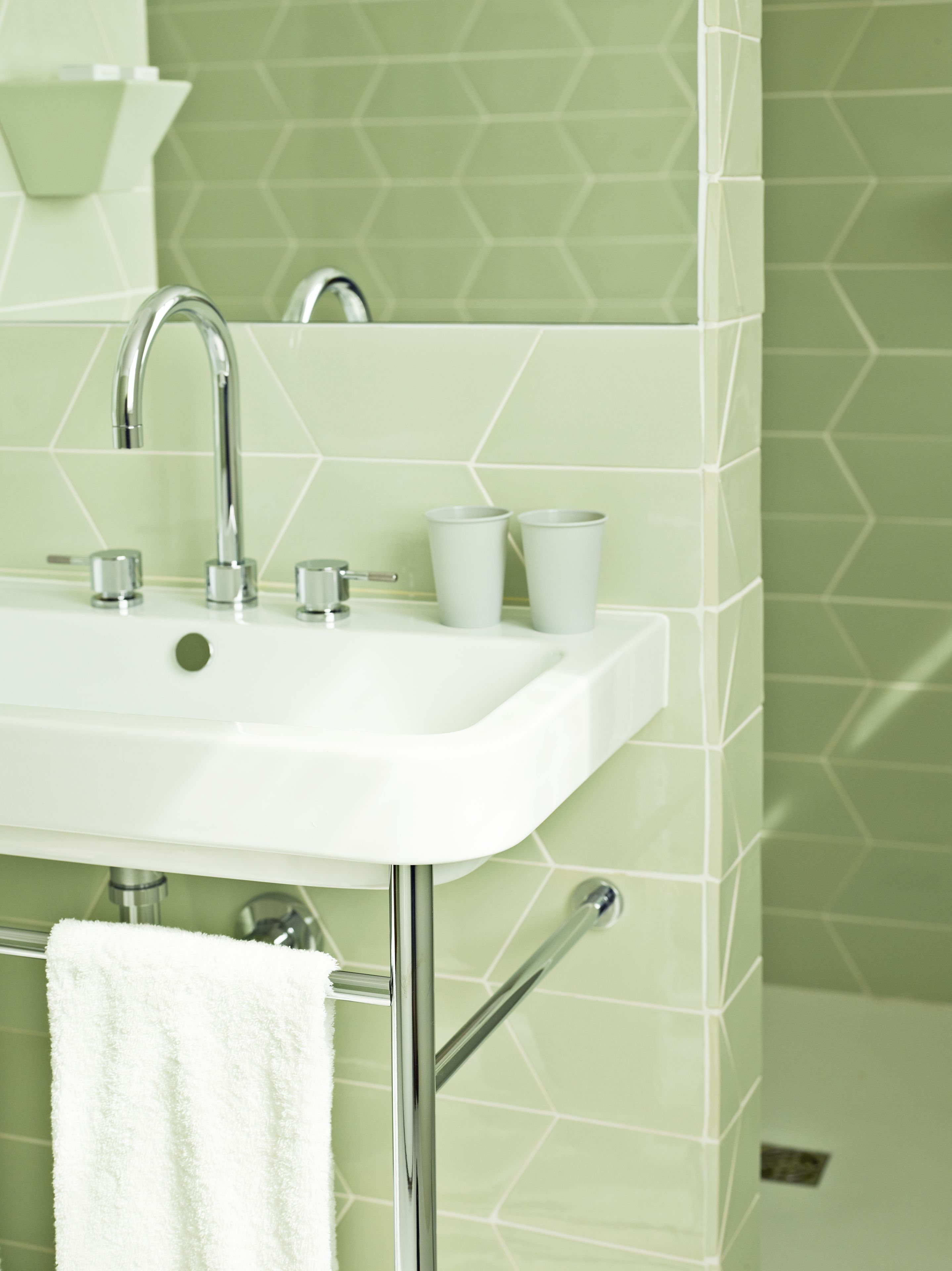 A bathroom with a white sink, chrome faucet, and towel rack.
