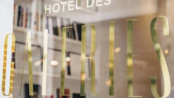 A hotel sign with the name "HOTEL DES GALLERIES" in large, gold letters.