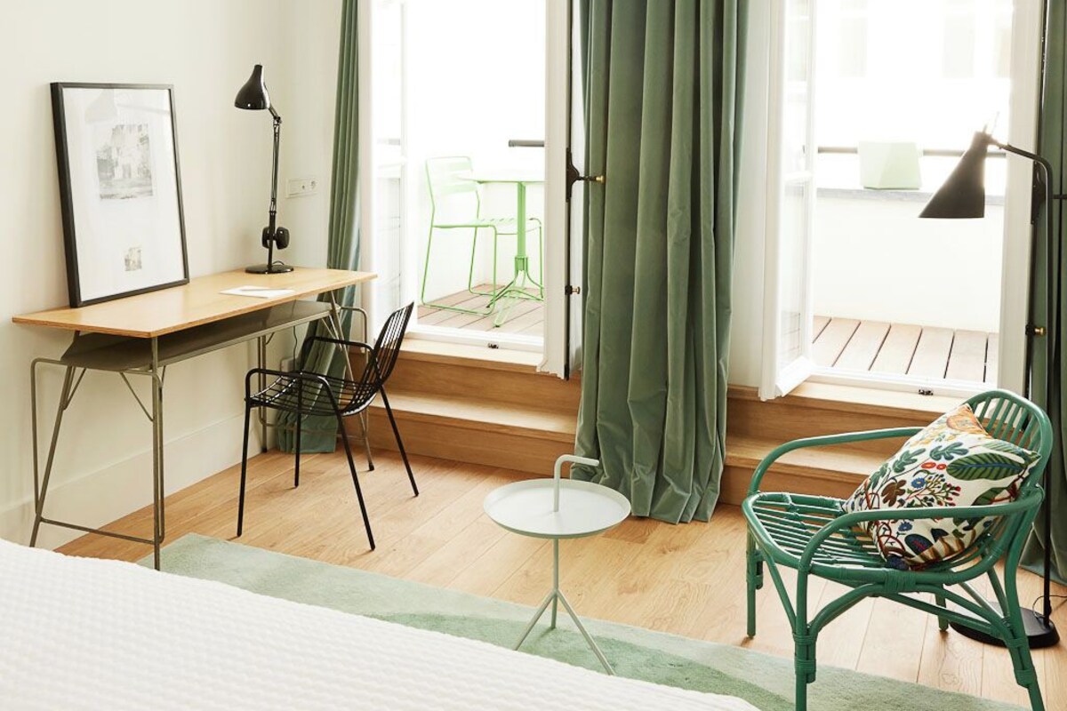 Un dormitorio con cama, escritorio, silla y vistas al balcón.