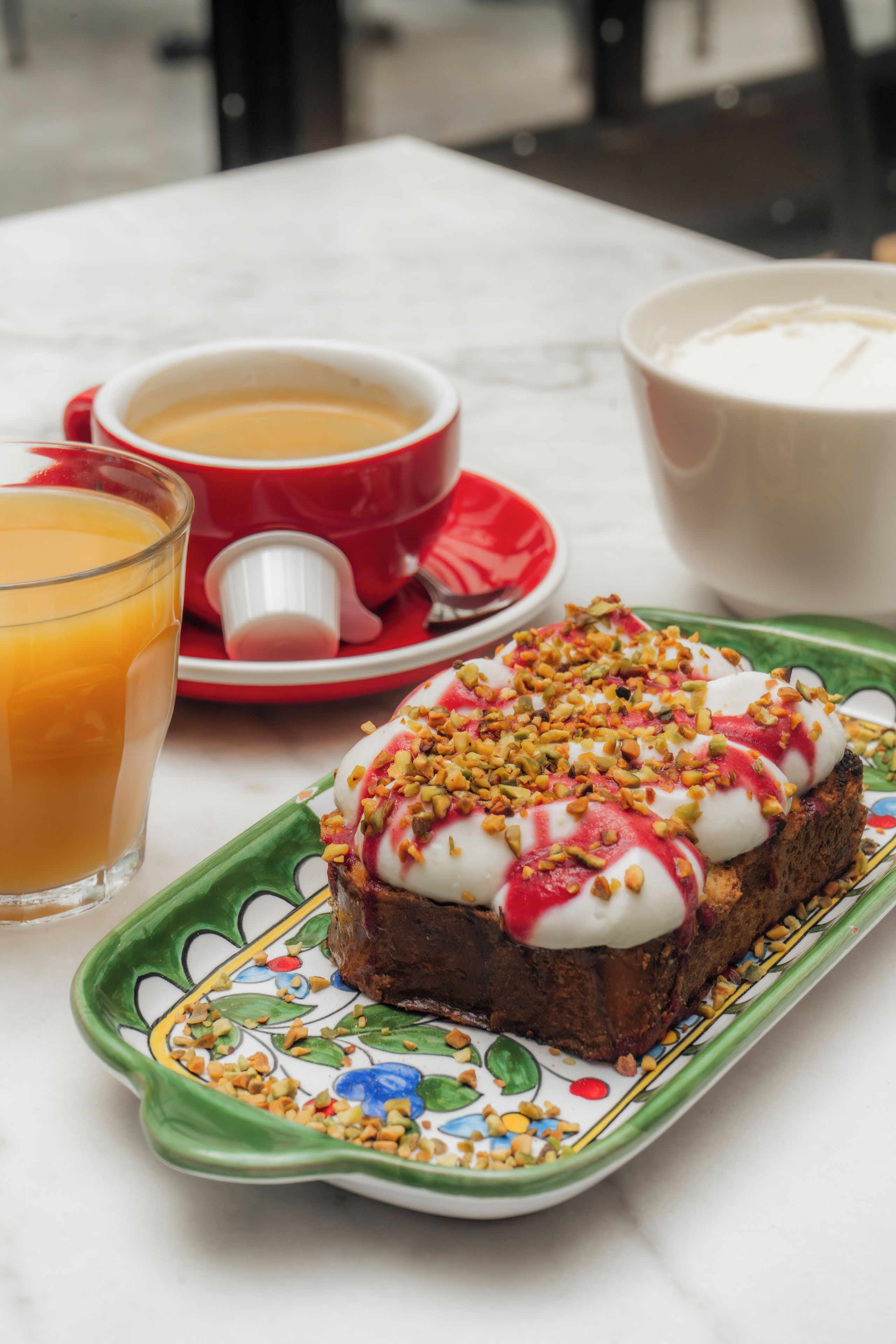 A breakfast setting with a plate of food, a glass of orange juice, and a bowl of soup.