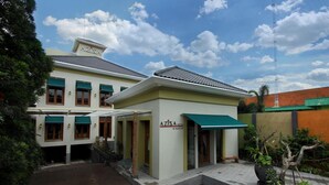 A hotel with a green awning, a covered entrance, and a paved courtyard.