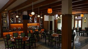 A restaurant with wooden beams, hanging pendant lights, and a tiled floor.