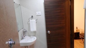 A bathroom with a white sink, a mirror, and a towel hanging on a rack. - Krishna Avatar Stay Inn (Navi Mumbai)