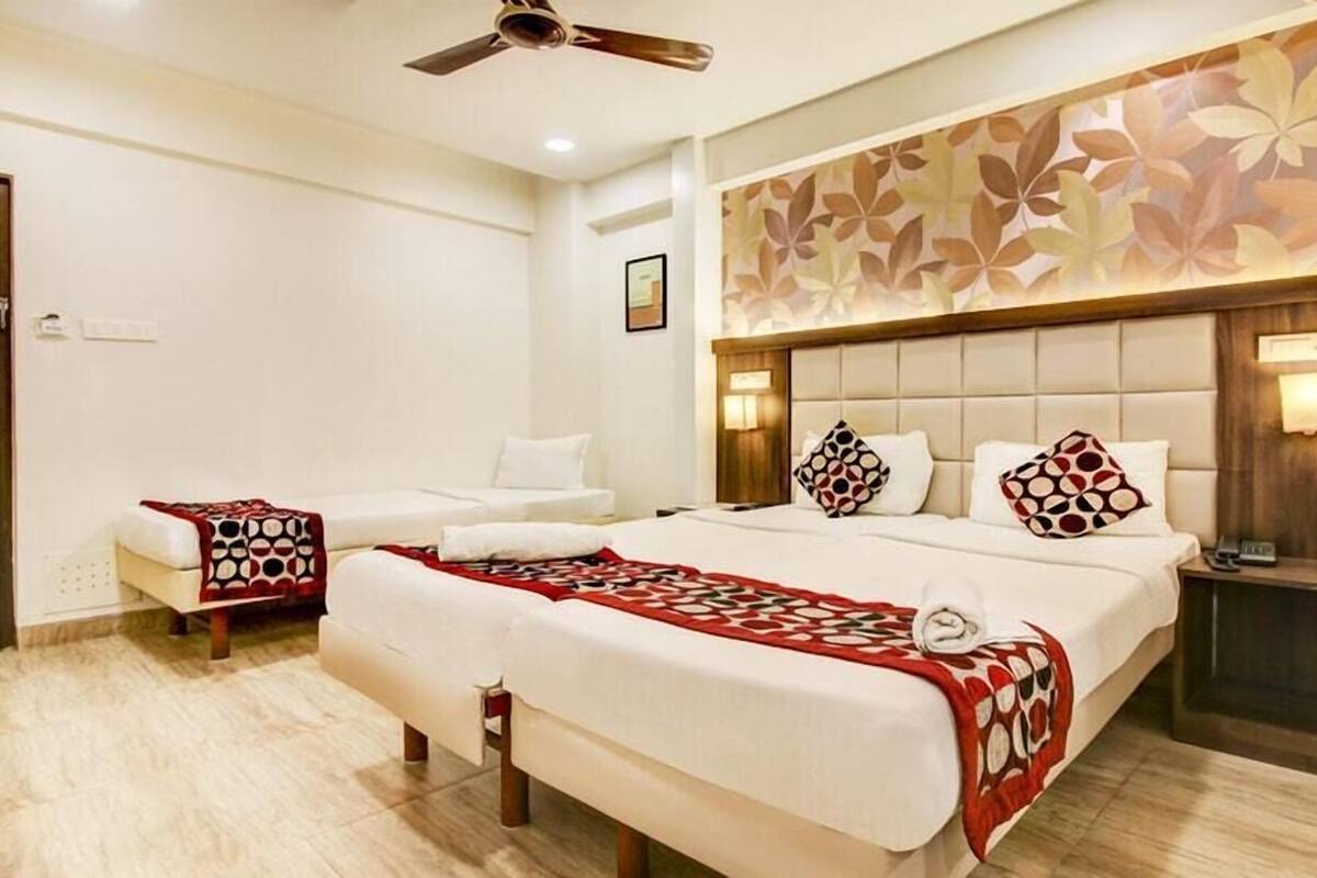 A hotel room with a large bed, a bedside table, a chair, and a ceiling fan.