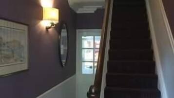 Una escalera con barandilla de madera y peldaños alfombrados oscuros.