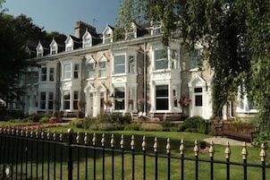 A large, white, multi-story building with a symmetrical facade, featuring multiple windows and a central entrance.