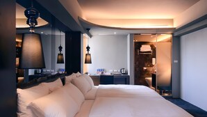 A modern hotel room with a large bed, a desk with a lamp, and a bathroom visible through an open door. - Kiwi Express Hotel - Jiuru (Kaohsiung)