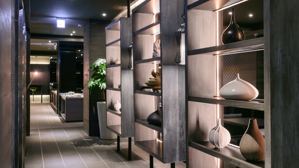 A modern interior with wooden shelving displaying decorative vases and a potted plant. - Kiwi Express Hotel - Jiuru (Kaohsiung)