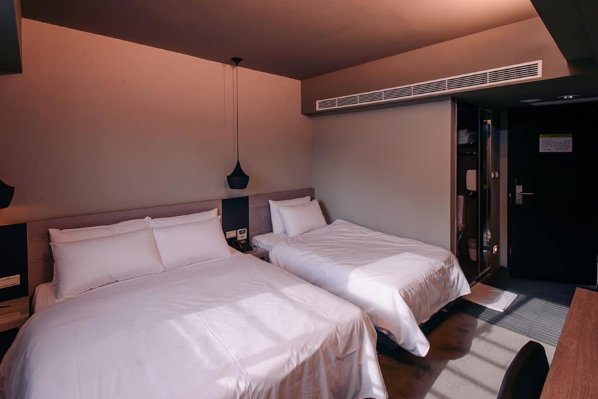 Ein Hotelzimmer mit zwei Betten, einem Schreibtisch und einer Tür.