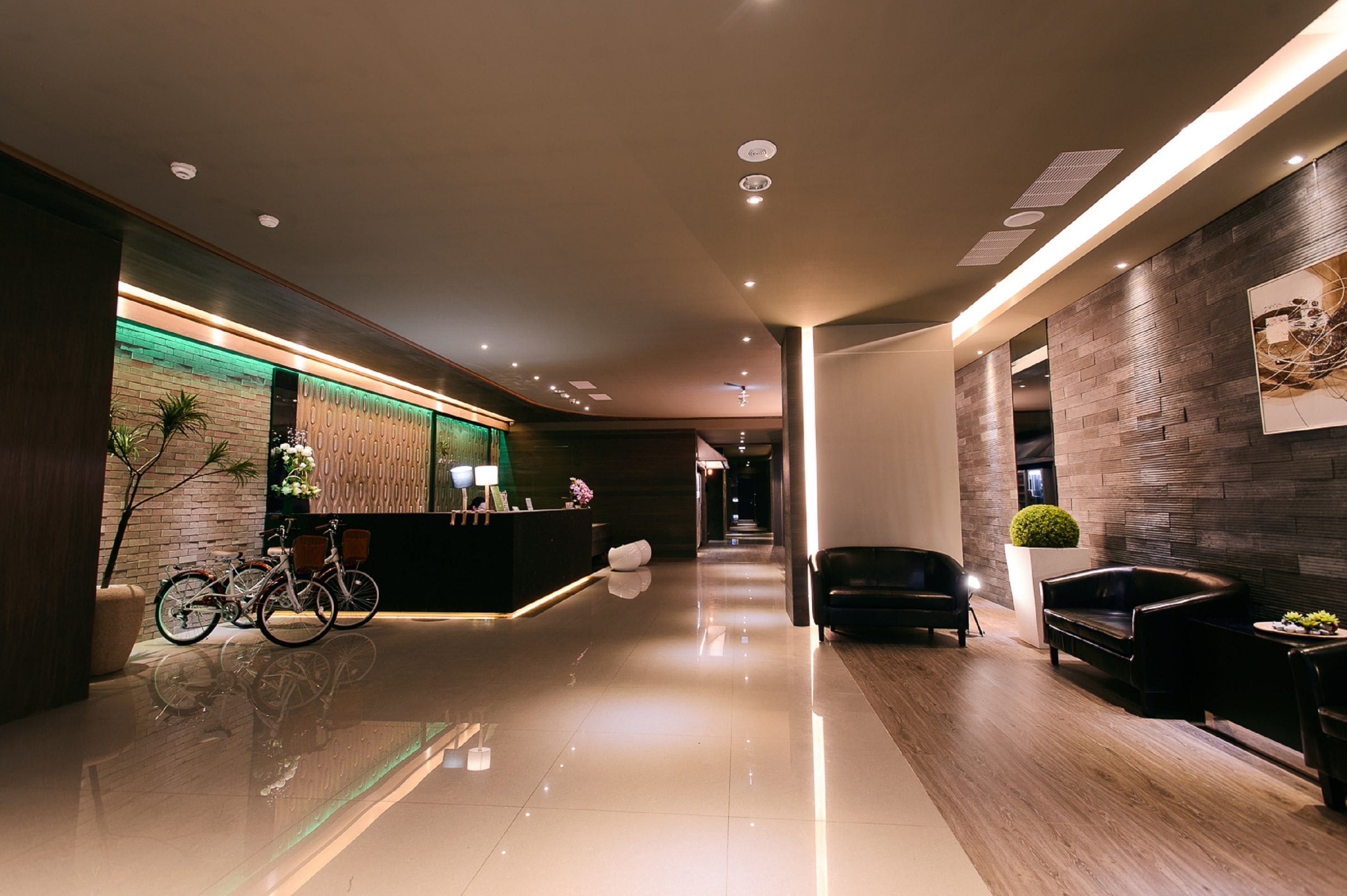 A modern hotel lobby with a reception desk, seating area, and a bike rack.
