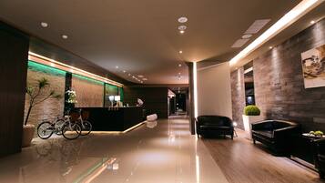 A modern hotel lobby with a reception desk, seating area, and a bike rack.