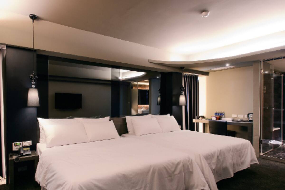 Ein modernes Hotelzimmer mit einem großen Bett, einem Schreibtisch und einer Duschkabine aus Glas.
