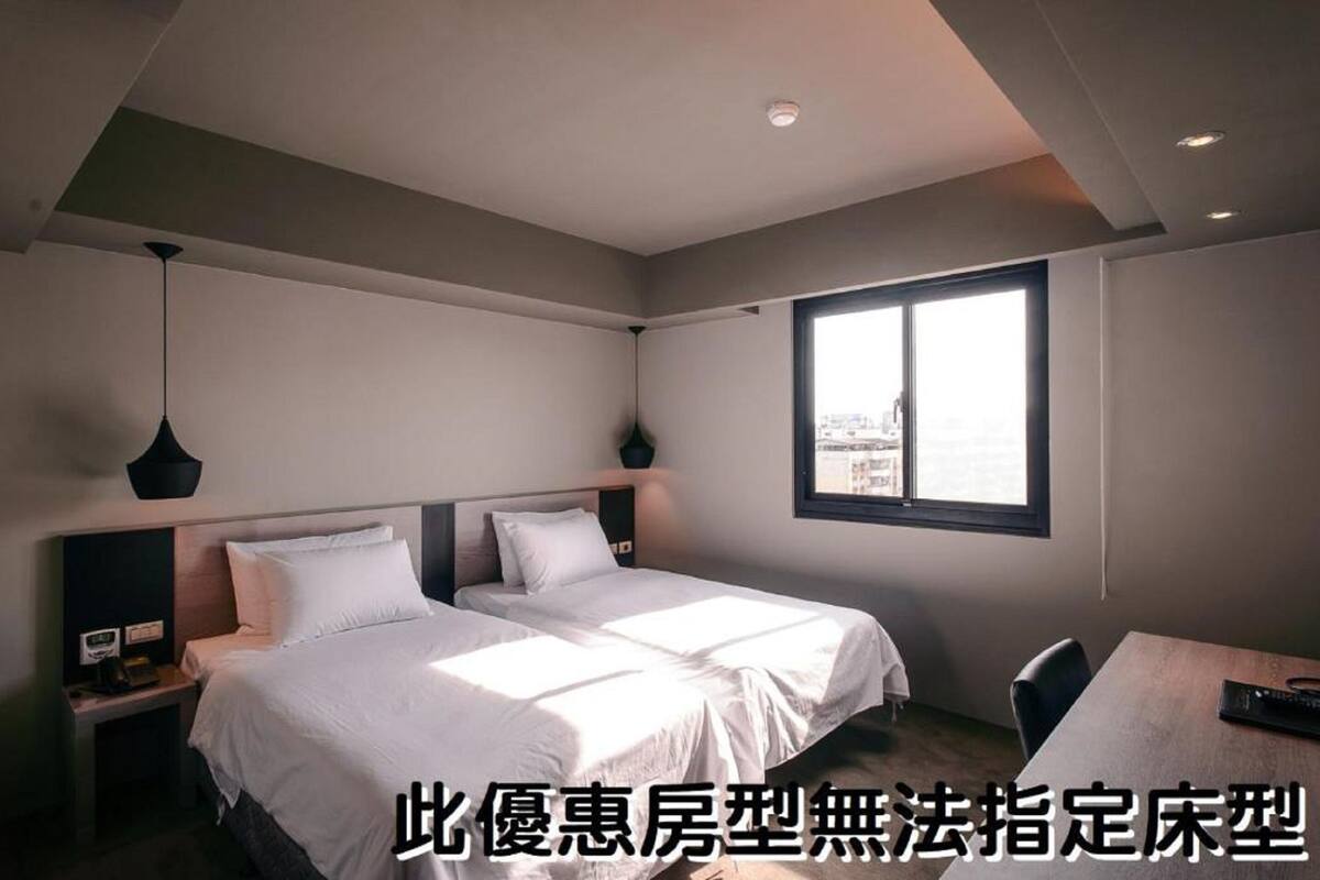 Ein modernes Hotelzimmer mit einem großen Bett, Nachttischen, einem Schreibtisch und einem Fenster mit Blick auf die Stadt.