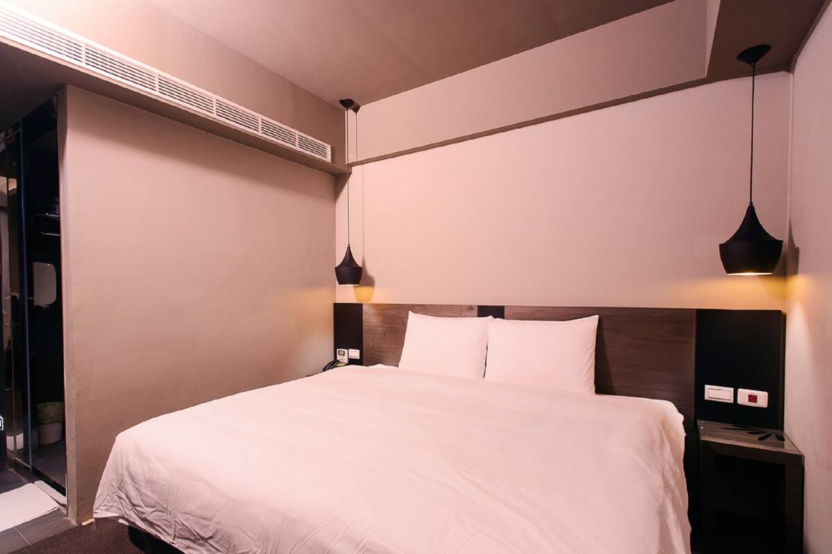 Ein ordentlich bezogenes Bett mit weißen Laken in einem modernen Hotelzimmer.