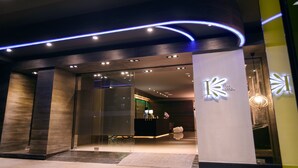 The exterior of a hotel with a modern design, featuring a reception area with a counter and a logo. - Kiwi Express Hotel - Jiuru (Kaohsiung)