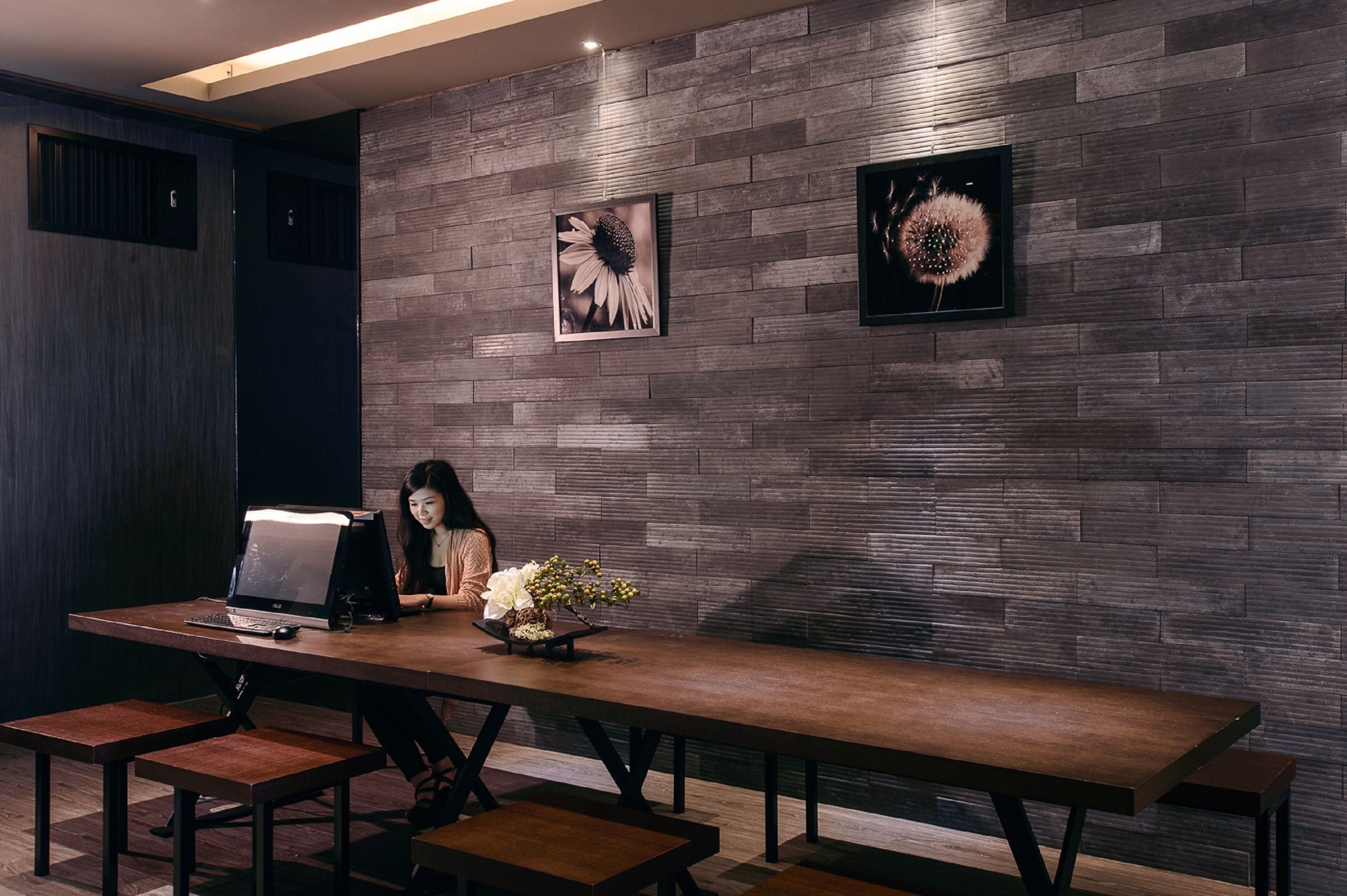 Un comedor moderno con una mesa de madera larga, bancos y una pared decorada con cuadros de motivos florales.