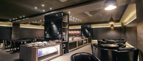 A modern restaurant with a central counter, black leather seating, and recessed lighting.