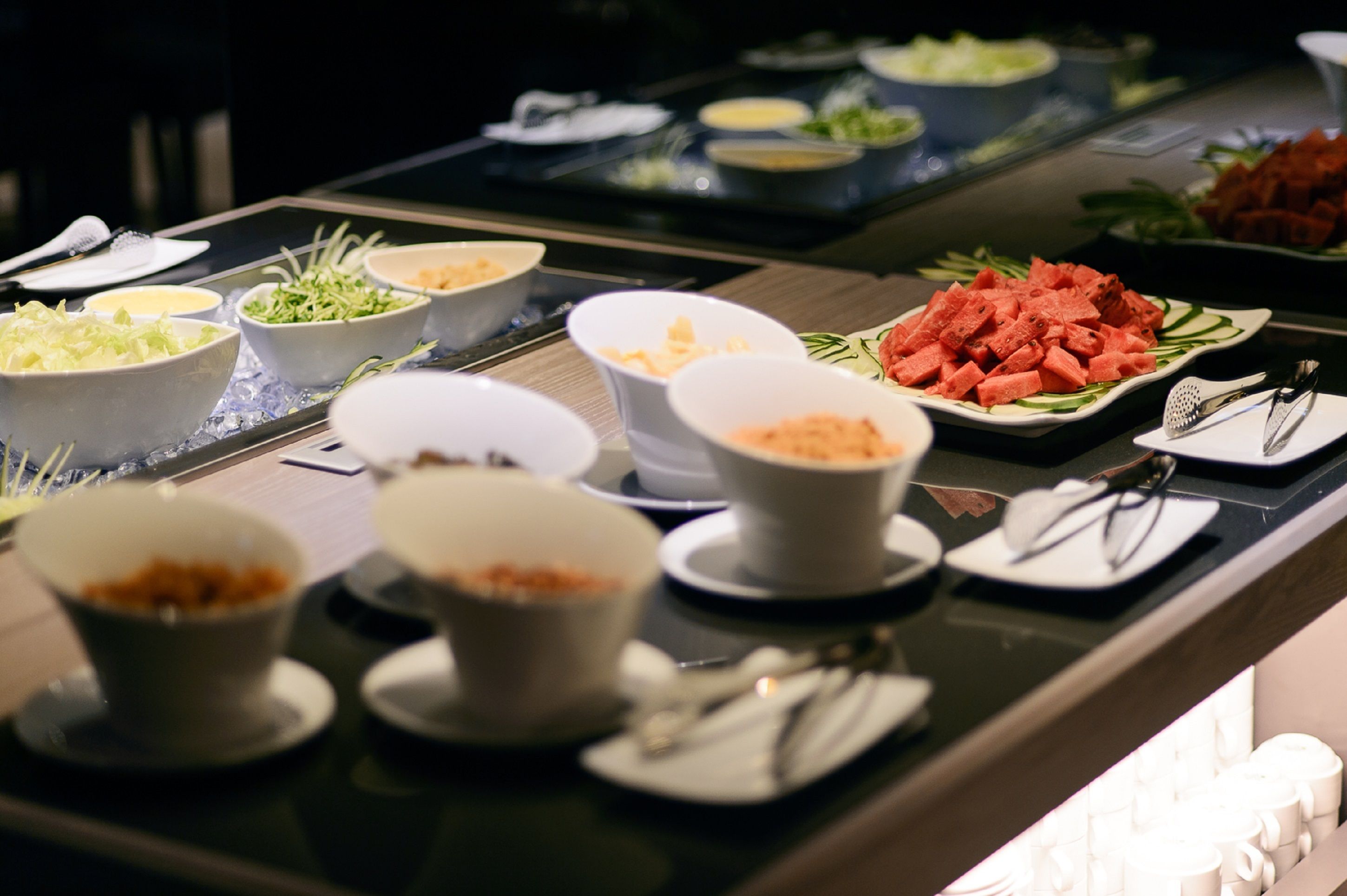 A buffet with various dishes including salads, vegetables, and a watermelon dish.