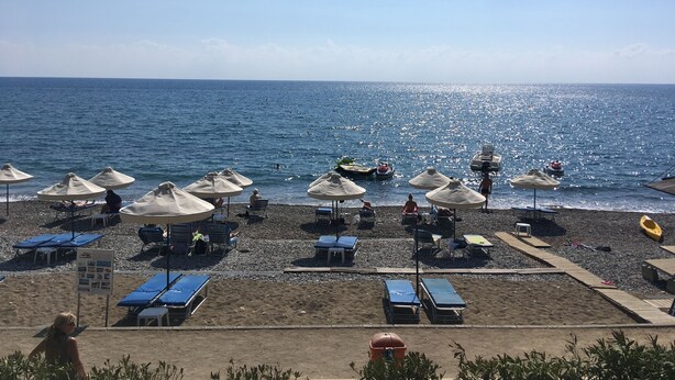 Une plage avec des parasols, des chaises longues et une vue dégagée sur la mer.