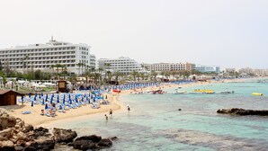 Um resort à beira-mar com vários edifícios de hotel, espreguiçadeiras e barcos.