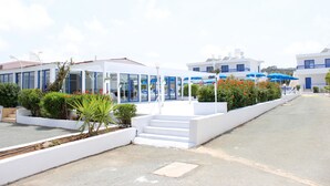 Um edifício branco com fachada de vidro e telhado azul.