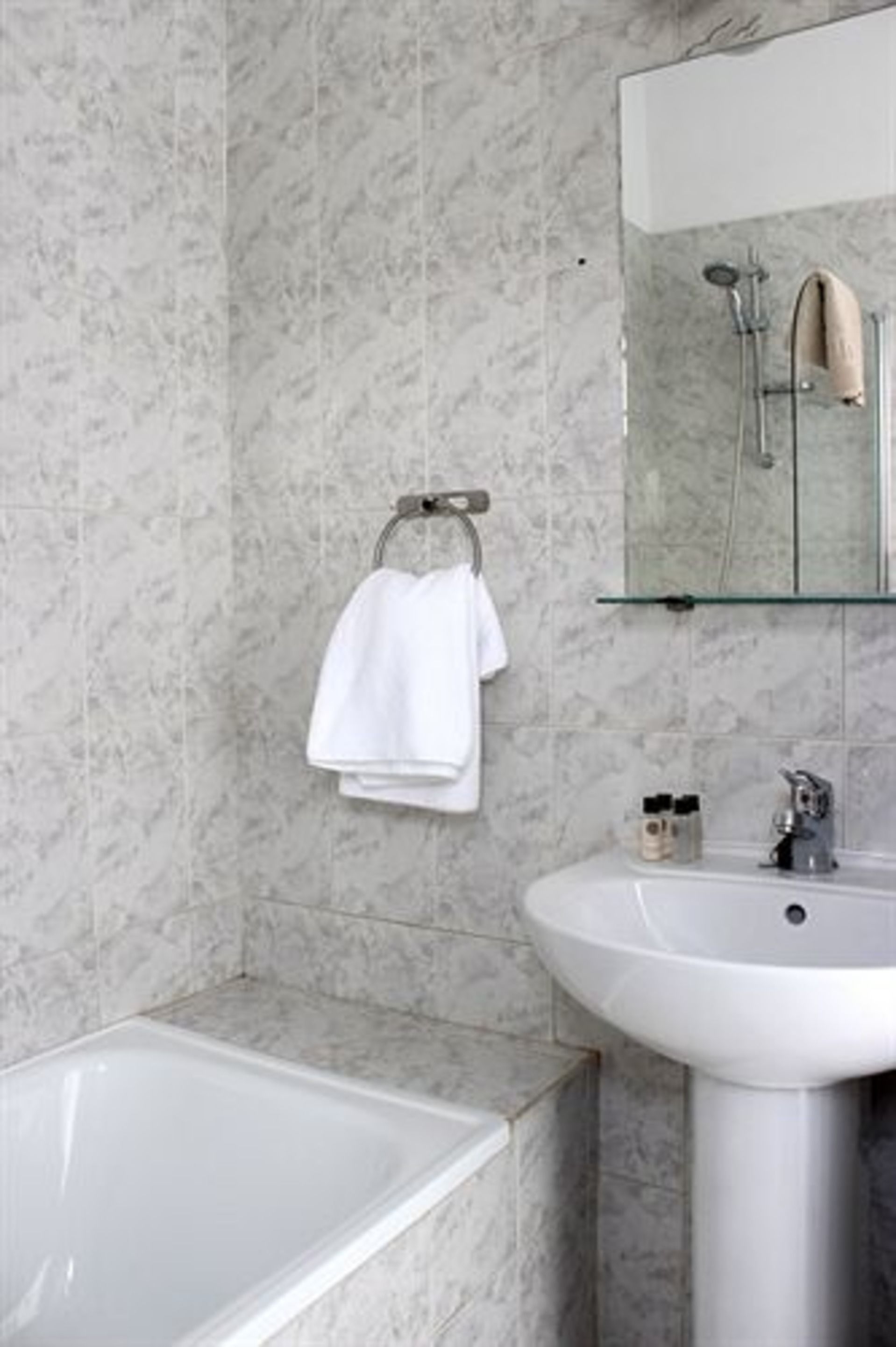 A bathroom with a marble wall, a white sink, and a bathtub.