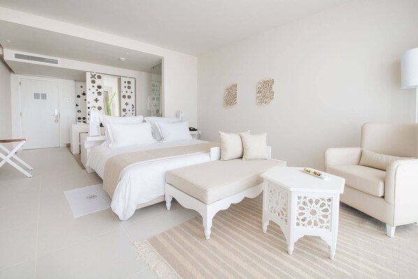 Une chambre spacieuse avec un grand lit, un canapé et une petite table.