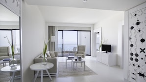 A modern, well-lit living room with a sofa, coffee table, and a TV on a cabinet. - La Badira - Adults Only (Hammamet)