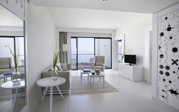 A modern, well-lit living room with a sofa, coffee table, and a TV on a cabinet.