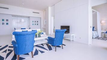 Een moderne woonkamer in een wit kleurenschema, met een zithoek, een salontafel en een televisie.