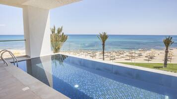 A swimming pool with a clear view of the beach and ocean.