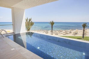 A swimming pool with a clear view of the beach and ocean.