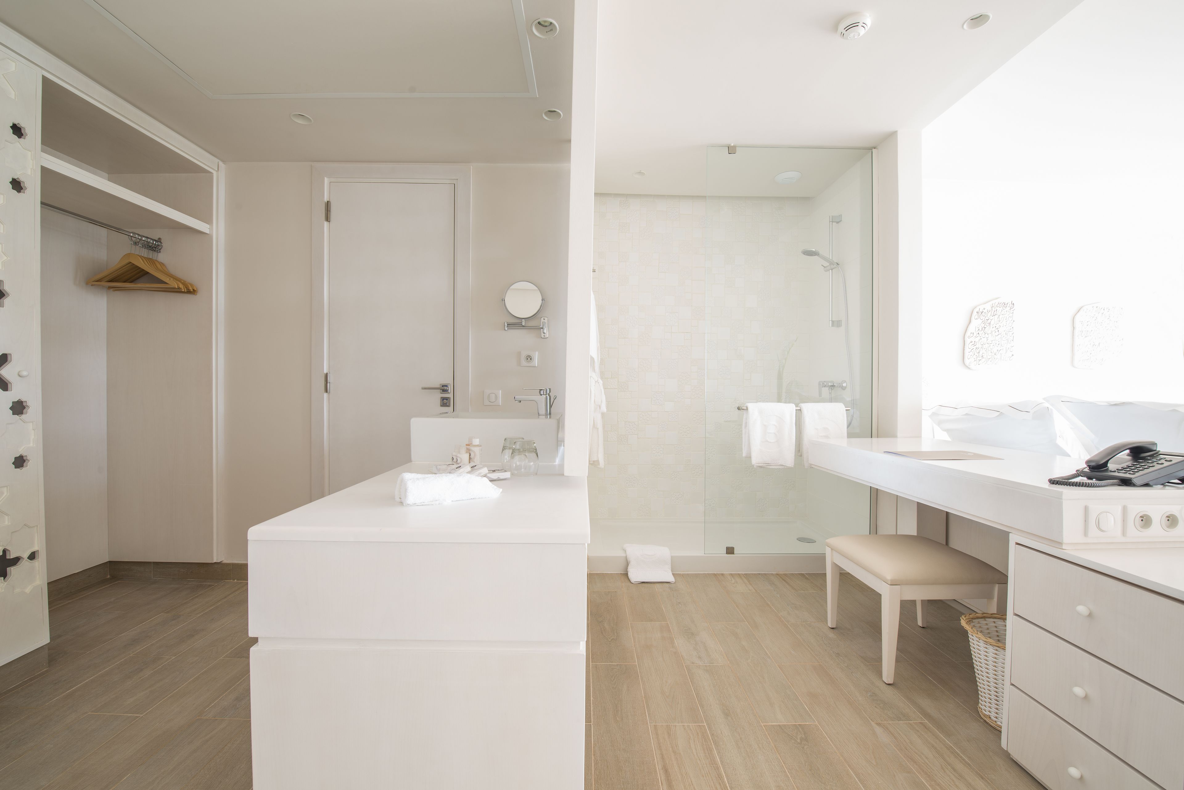 A modern bathroom with a white vanity, a shower, and a bench.