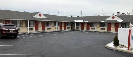Un motel avec une rangée de chambres, un parking et une voiture garée.