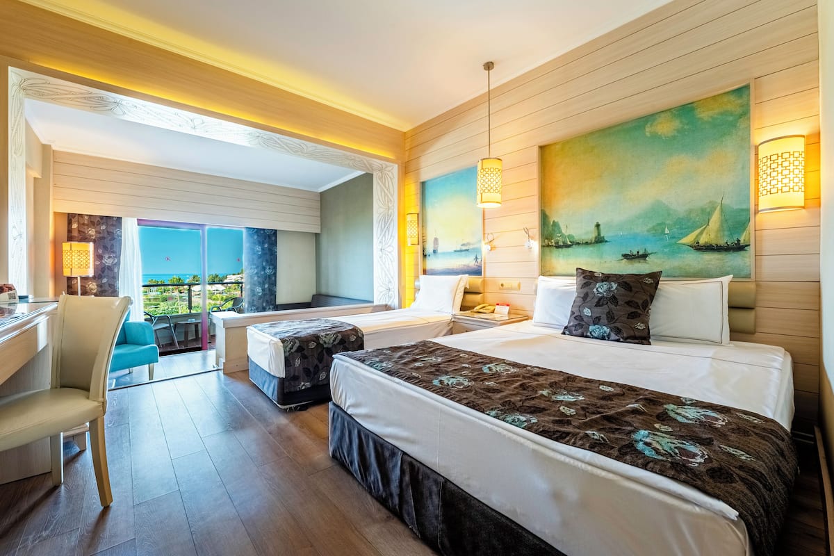 A hotel room with a large bed, a desk, and a view of the sea.