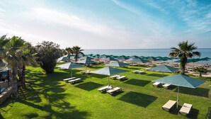 Une pelouse bien entretenue, agrémentée de tables de pique-nique et de parasols, avec vue sur une plage offrant une vue dégagée sur l’océan.