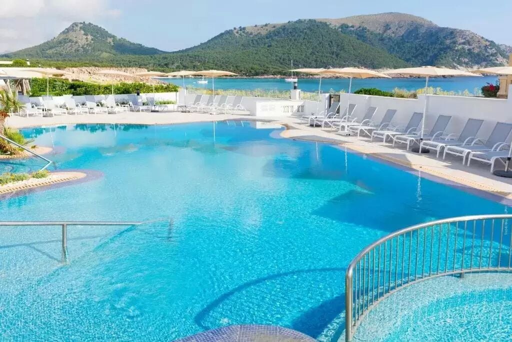 Una piscina al aire libre, sombrillas, sillones reclinables de piscina