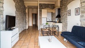 A living room with a TV, a sofa, and a dining area with chairs and a table. - Urbi Apartments (Manresa)